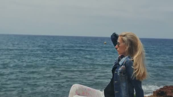 Мечтательная женщина, наслаждающаяся удивительным морским пейзажем на скалах — стоковое видео