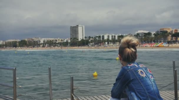 Dromerige vrouw zit op de trap en het genieten van geweldige zeegezicht en het strand op de rotsen — Stockvideo