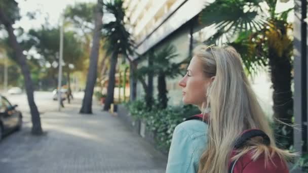 Молодая девушка с рюкзаком ходит по улицам в замедленной съемке — стоковое видео