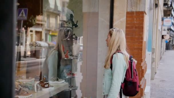 Compras - mulher jovem que olha em uma janela de loja — Vídeo de Stock