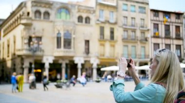 Kadın smartphone ile resim çekmek. Güneşli bir günde Meydanı'nda çekim smartphone kadınla