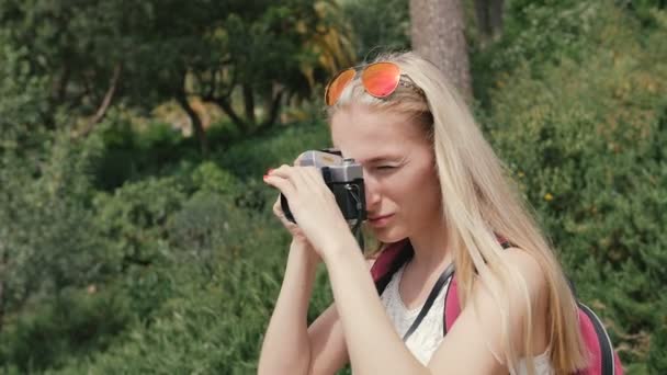 Mujer joven con cámara retro tomar fotos en el parque — Vídeo de stock