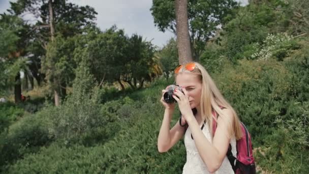 Mujer joven con cámara retro tomar fotos en el parque — Vídeos de Stock