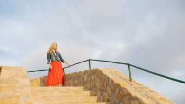 Romantik kız kırmızı etek yürümek sahil tarafındaki merdivenlerden aşağı