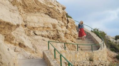 Romantik kız kırmızı etek yürümek sahil tarafındaki merdivenlerden aşağı