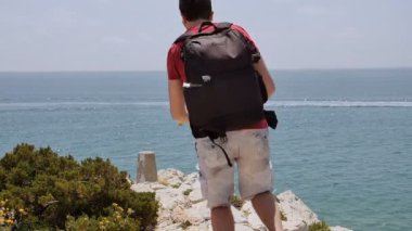 Sırt çantası ile genç adam kenarına kadar çalıştırın ve manzarası görünüyor.