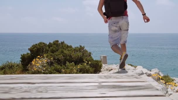 Fiatalember backpack futtassa a szélén, és néz ki a lenyűgöző kilátást a. — Stock videók