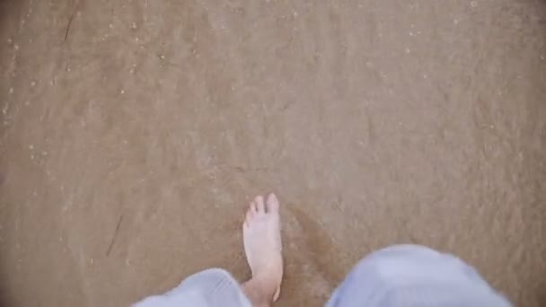 Man går barfota på sandstrand i ocean wave, perspektiv. — Stockvideo