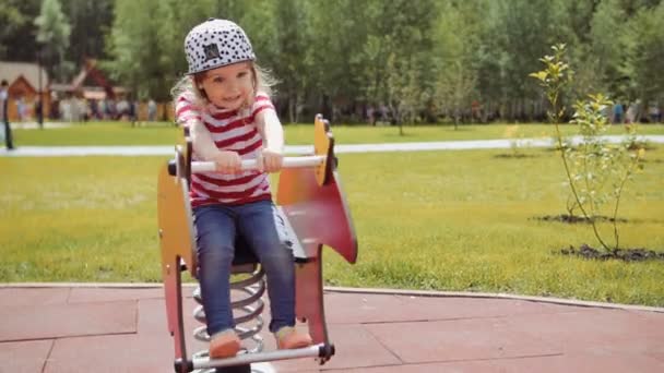 Маленькая девочка играет в парке сидеть на качелях — стоковое видео
