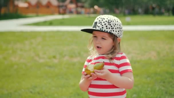 Chica soleada con pera comiendo fruta felizmente — Vídeo de stock