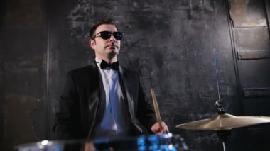 Siyah takım elbise ve davul güneş gözlüğü çalış adam. Baterist ile sahnede performans rock müzik grubu