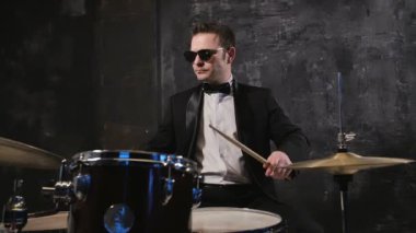 Siyah takım elbise ve davul güneş gözlüğü çalış adam. Baterist ile sahnede performans rock müzik grubu