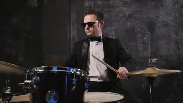 Homem de fato preto e óculos de sol toca tambor. Banda cover de rock se apresentando no palco com o baterista — Vídeo de Stock