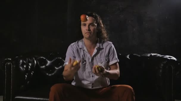 Людина в студії жонглює яблука і посміхається камері . — стокове відео