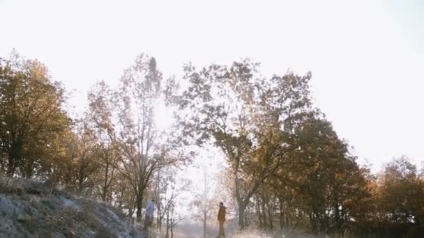 Een meisje loopt en springt in de armen van haar vriendjes op de heuvel op een dag frosty ochtend — Stockvideo