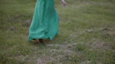 mutlu bir şekilde sıcak yaz gününde kaçmayı uzun saçlı genç esmer kadın. Doğa dışarıda tadını yeşil giysili güzel kadın giyinmiş.