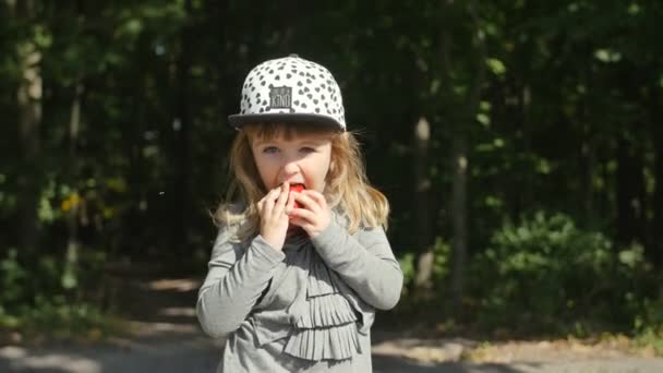 Petite fille portrait manger pomme rouge en plein air — Video