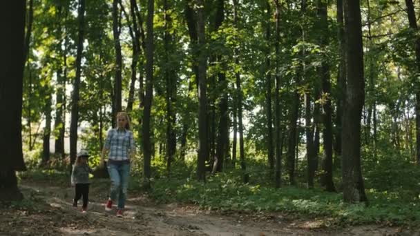 Mutter und Baby gehen auf Landstraße im Kiefernwald spazieren — Stockvideo