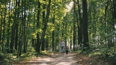 Anne ve bebek kırsal yol orman ve sonra kız kameranın doğru yönetilen ülke üzerinde yürümek
