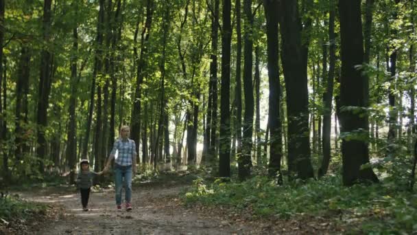 Mother and baby walk on country rural road in forest and then girl run toward the camera — Stock Video