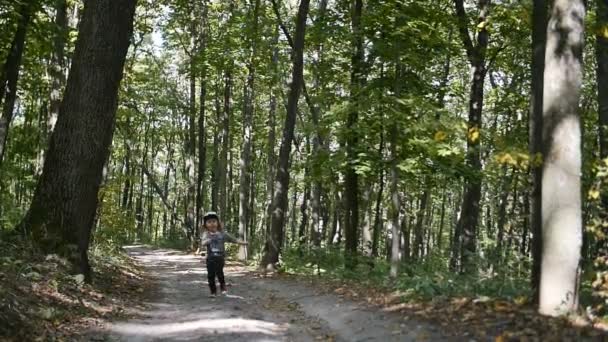 Маленька дівчинка біжить вперед у лісі — стокове відео