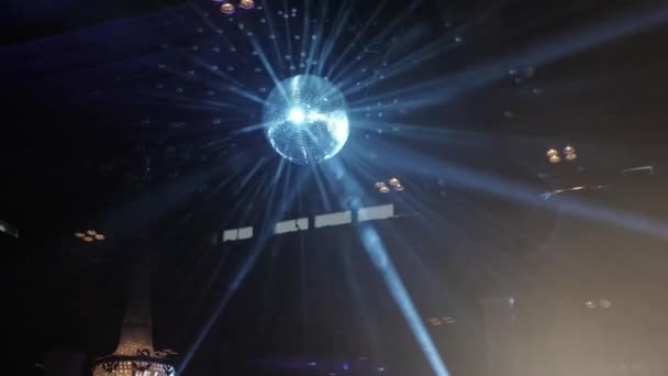 Spiegel disco bal spinnen en weerkaatsen blauwe stralen van licht in een nachtclub — Stockvideo