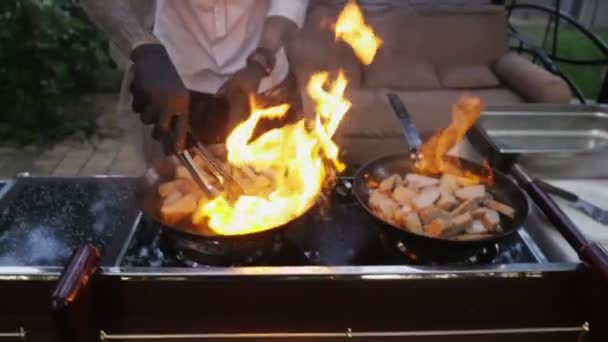 Chef cooks meat on an open fire in a burning pan outdoors in slow motion — Stock Video