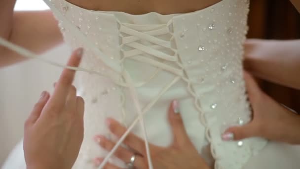 Bridemaids helping the bride to put her wedding dress on — Stock Video