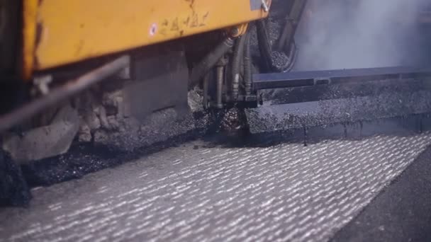 Asphaltfertiger trägt Asphalt auf der Autobahn auf. Ein Gerät zum automatischen Aufbringen von Asphalt auf der Straße. Riesiges schweres Gerät bringt Asphalt auf die Straße. — Stockvideo