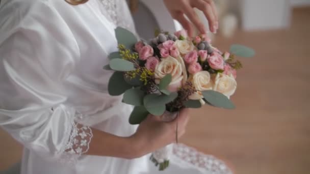 Beautiful woman in bathrobe looking at wedding bouquet — Stock Video