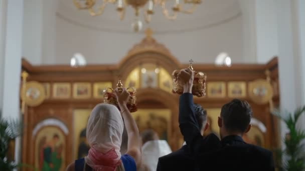 Pasgetrouwden zijn in de kerk van het altaar. Priester zegent paar. Orthodoxe huwelijksceremonie — Stockvideo