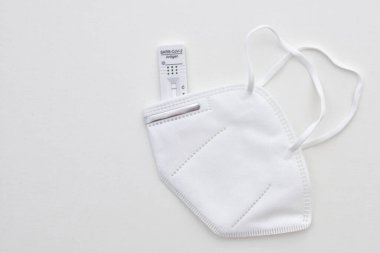 İzole edilmiş korona virüsü koruyucu ffp2 yüz maskesi ve hızlı antijen testi arka planı kopyalama alanı