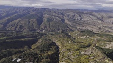 Görkemli dağların çarpıcı bir hava perspektifi, yemyeşil vadileri ve dramatik arazileri sergiliyor.