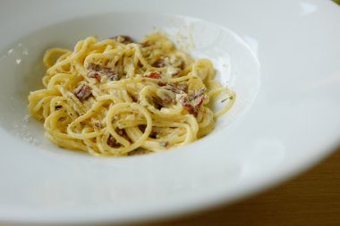 Spagetti carbonara krema sos ve pastırma beyaz plaka üzerinde