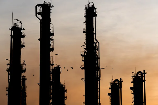 La puesta de sol detrás de la planta de gas natural dejando silueta mirada en la torre — Foto de Stock