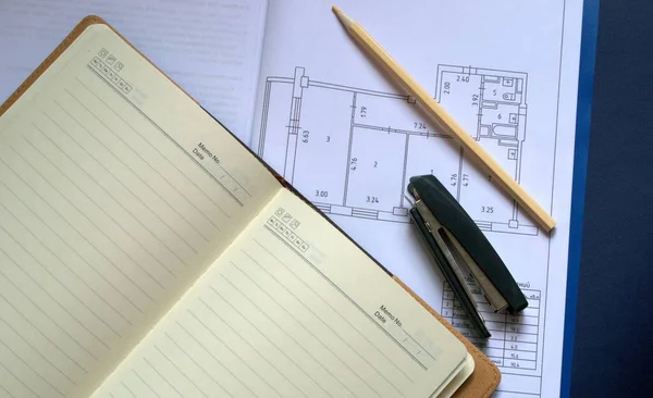 İnşaat projesi, apartmanın yeniden inşası. Kağıt üzerinde bir plan. Masaya kalem ve zımba koyun.