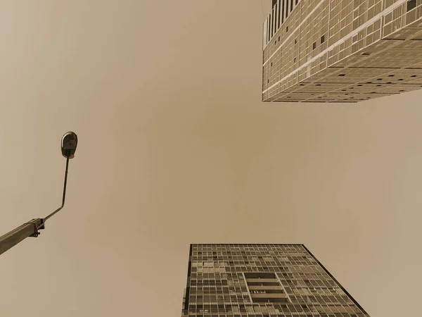 Dipteki manzara. Uzun binalar, gökdelenler ve gökyüzüne karşı bir sokak lambası. Şehrin kahverengi gölgeleri..