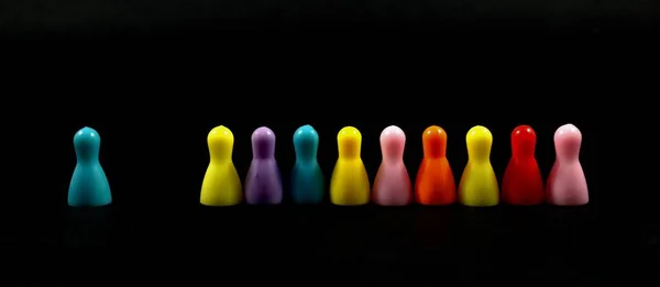 Colorful chips for the children\'s game stand in a row on a black background. One chip is located away from the rest