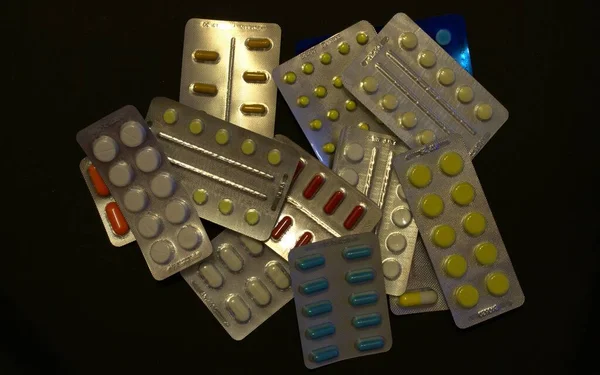Pakette bir sürü renkli hap var. Siyah bir arkaplana dağılmış