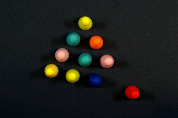 Multi-colored chips for children\'s game are laid out in the shape of a triangle. The leader chip came forward. Not in the system. Dark background