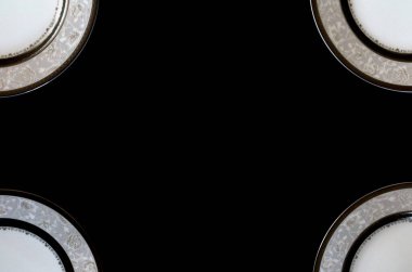 Fotoğrafın köşesinde dört tabak var. Siyah arkaplan üzerindeki tablo plakalarının çerçevesi