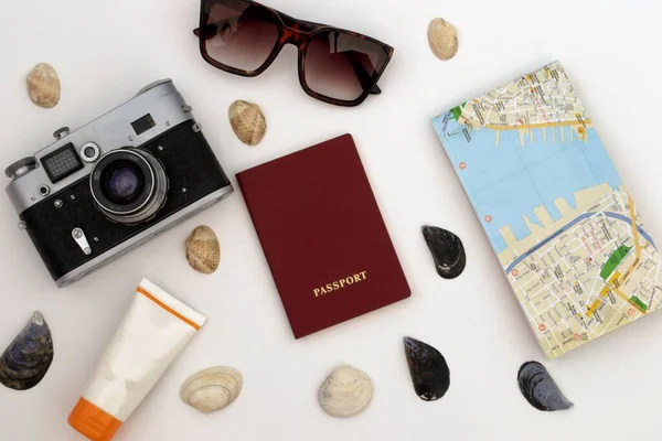 Items for recreation and travel. Sunglasses, sunscreen, camera, map, passport and shells