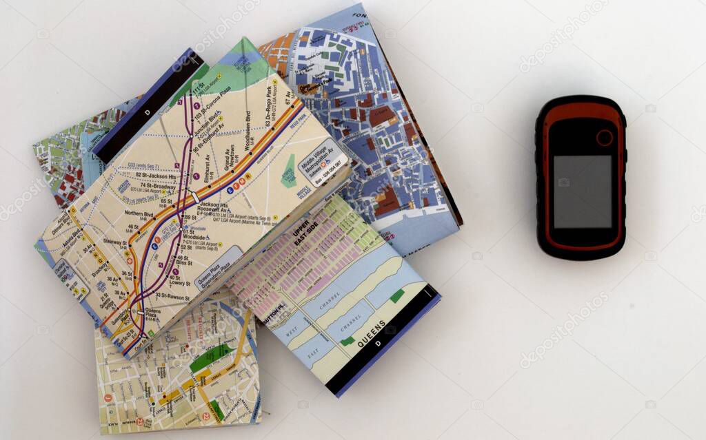 A stack of paper travel maps and an electronic satellite navigator on a white background
