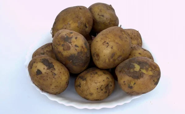Kirli Patatesler Beyaz Arka Planda Bir Tabakta Yemek Pişirmeye Hazırlanıyor — Stok fotoğraf