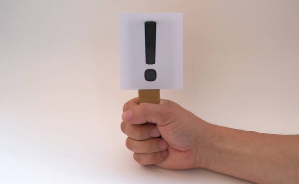 A white sign with an exclamation mark in his hand on a white background