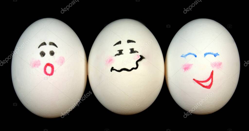 Three white chicken eggs with painted faces on a black background