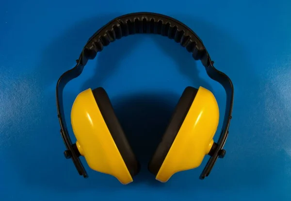 Mavi arka planda sarı kulaklıklar. Gürültü koruması