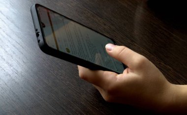 Bilgiyi görmek için bir kadının eli telefonu tutar.