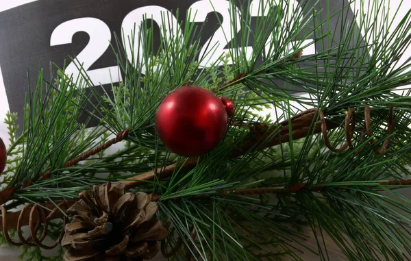 Kırmızı bir Noel topu ve dalda bir koni. Yeni yıl dekoru. 2022 yılı arka planda..