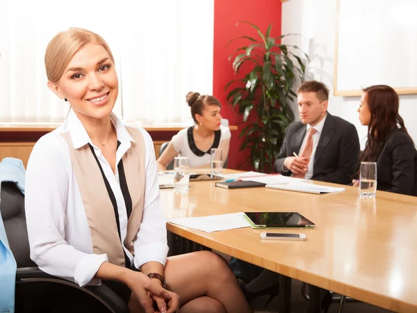 Mujer de negocios feliz con colegas en el fondo — Foto de Stock